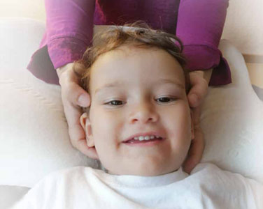 Zufriedenes Kind während einer Osteopathie Behandlung am kopf